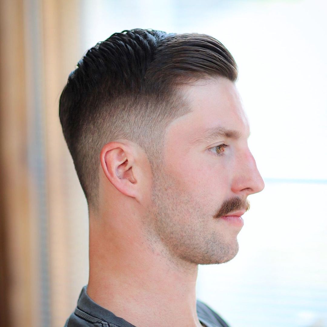 Mid fade haircut with cool slick hair and a mustache